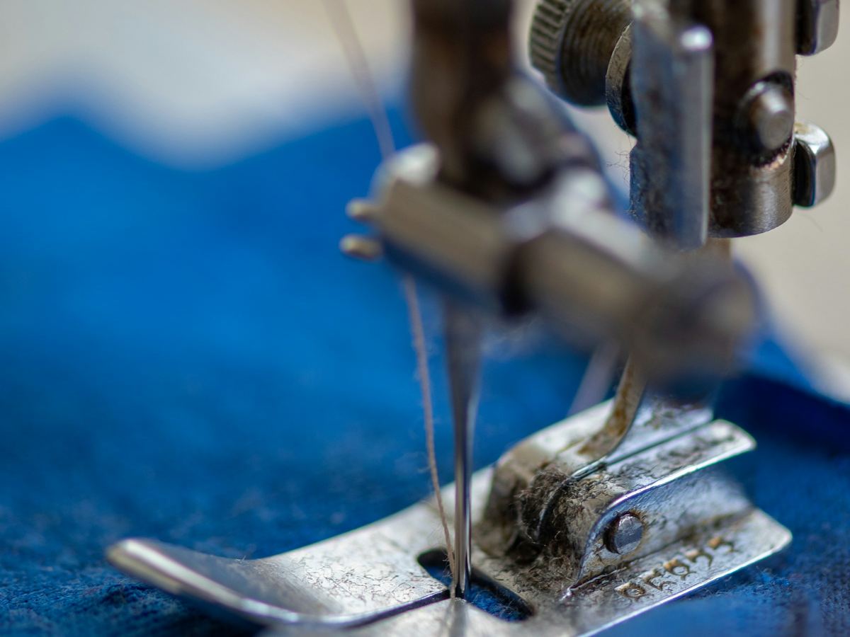Close view of a sewing machine needle and presser foot on fabric