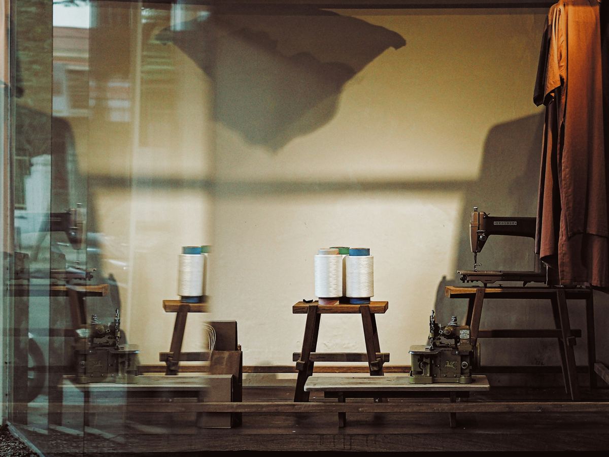 Spools of thread on wooden stools in a workshop window